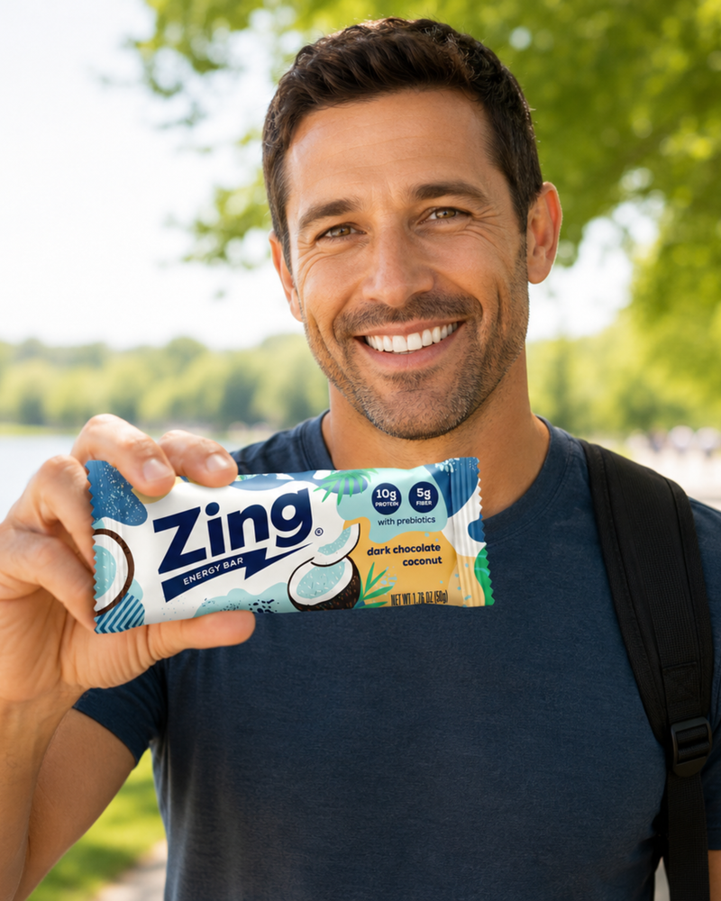man enjoying a dark chocolate coconut zing energy bar after a walk in a sunny park