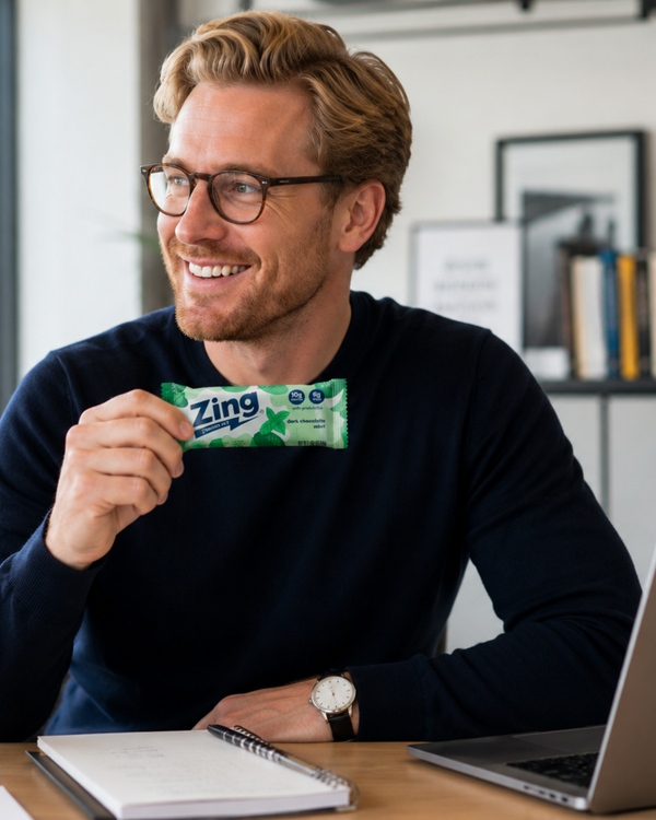 professional holding a dark chocolate mint zing energy bar while working at a desk